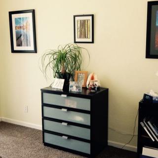 A neatly organized interior space featuring a modern dresser, framed art on the walls, and a potted plant for decoration.