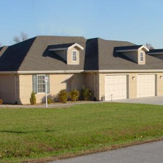 A view of a charming duplex with a well-maintained lawn in a suburban area.