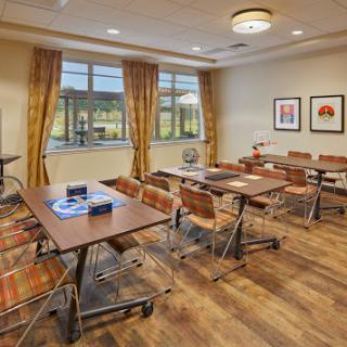 A well-lit meeting room with modern furnishings, featuring tables and chairs arranged for group activities.