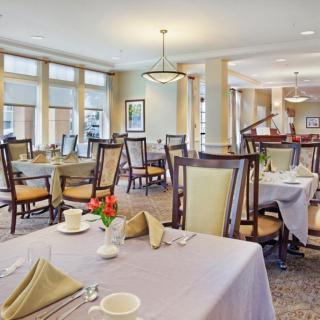 A spacious and elegantly designed dining room with neatly arranged tables and chairs, featuring large windows and soft lighting.
