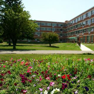 A landscape view of a building with a flower garden in the foreground.