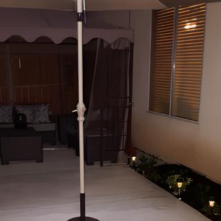 A cozy outdoor patio area at night featuring furniture, subtle lighting, and an umbrella stand.
