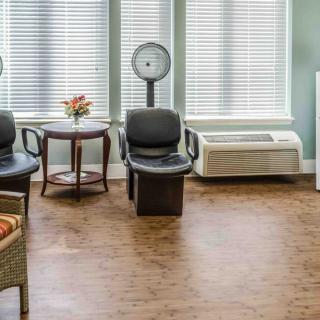 A well-lit waiting room with chairs, a scale, and a small table with flowers.