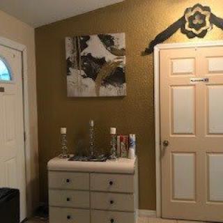 A well-decorated entryway featuring a dresser, artwork on the wall, and a closed door.