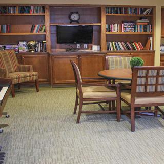 A cozy library room with bookshelves, a table, and chairs.