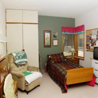 A cozy bedroom with a bed, armchair, and various decorations.