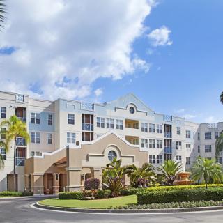 A large residential building with palm trees under a clear blue sky.