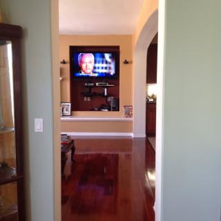 A view into a living room with a television mounted on the wall and a wooden floor.