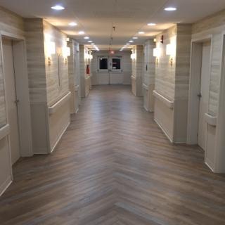 A view of a well-lit interior hallway with multiple doors and a wooden floor design.