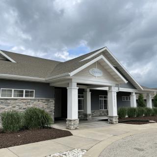 A modern residential building with a gray facade and white pillars under a cloudy sky.