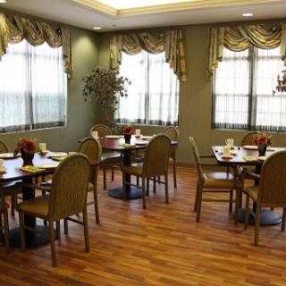 A cozy dining area featuring neatly arranged tables and chairs, complemented by natural light from the windows.