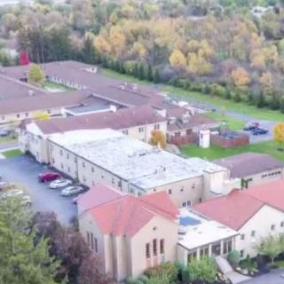 Aerial view of a campus with multiple buildings surrounded by trees.