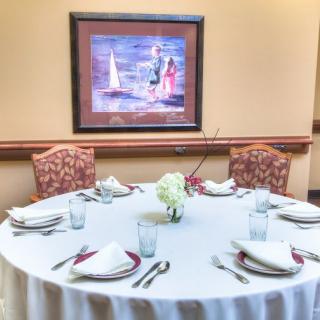 An elegantly set dining table with a centerpiece and surrounding artwork in a restaurant setting.