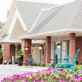 A charming brick building with a colorful garden and benches out front.