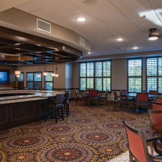 A restaurant interior featuring a bar area with seating and decorative carpeting.