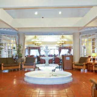 A spacious hotel lobby featuring a central fountain, comfortable seating, and elegant chandeliers.