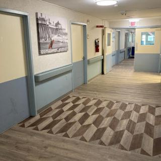 A well-maintained interior hallway with painted walls, decorative artwork, and patterned flooring.