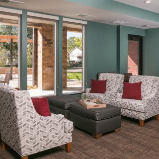 A cozy seating area with patterned armchairs and a central ottoman in a modern living room.