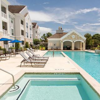A luxurious outdoor swimming pool area at a resort on a sunny day.