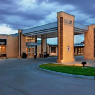 A modern hotel entrance with a welcoming driveway and cloudy sky.