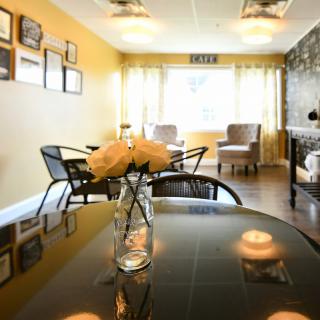 A modern living room with a dining table, decorated with flowers and ample natural light.