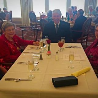 A group of people sitting at a dining table during a formal event.