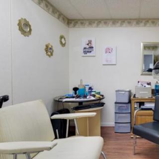 A cozy hair salon interior with chairs, beauty products, and wall decorations.