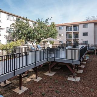 An outdoor view of an apartment complex with balconies and a landscaped area featuring trees.