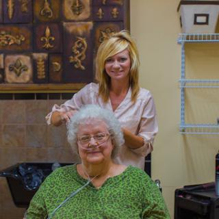 A hairstylist giving a stylish new look to an elderly woman in a warm and inviting salon.