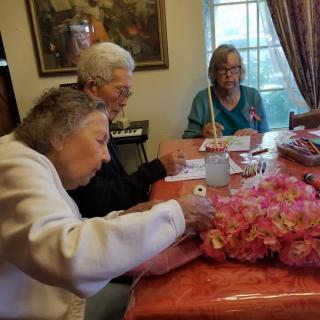 A group of seniors engaged in a crafting and painting activity together indoors.