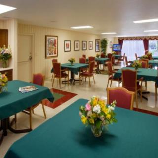A well-lit dining room with teal tablecloths and floral centerpieces.