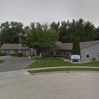 A suburban residential house with a well-maintained lawn and surrounding trees.