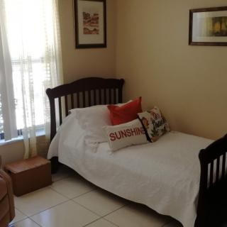 A cozy bedroom with a twin bed, neatly arranged pillows, and decorative artwork on the walls.
