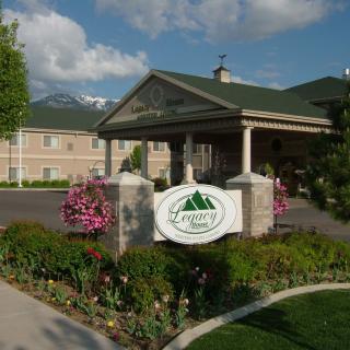 Entrance of a hotel adorned with flowers and greenery, featuring a sign with mountain imagery.