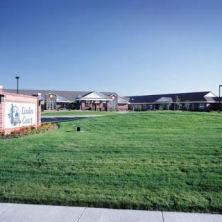 A well-maintained institutional building surrounded by green grass under a clear blue sky.