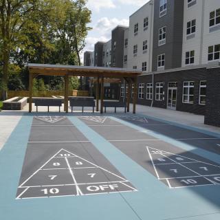 An outdoor shuffleboard court next to an apartment building on a sunny day.