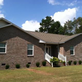 A suburban brick house with a well-maintained lawn under a clear blue sky.