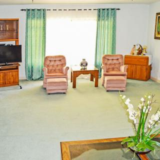 A cozy living room with armchairs, a television, and decorative elements.