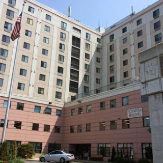 A multistory residential building with a flag in the foreground.