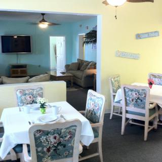 A cozy dining area with tables and chairs, adjacent to a living room featuring a sofa and television.