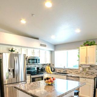 A modern kitchen featuring stainless steel appliances, granite countertops, and bright lighting.