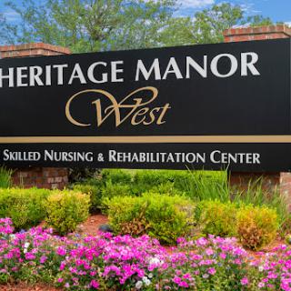 Signage for Heritage Manor West, a skilled nursing and rehabilitation center, surrounded by vibrant flowers.