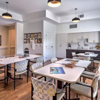 A modern meeting space with tables, chairs, and a kitchen area.