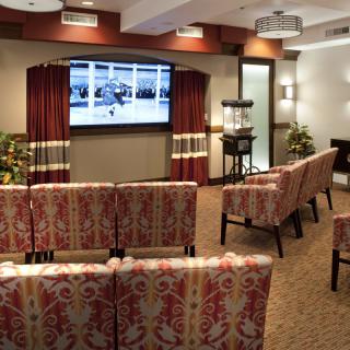 A cozy theater room with patterned seating facing a large screen.