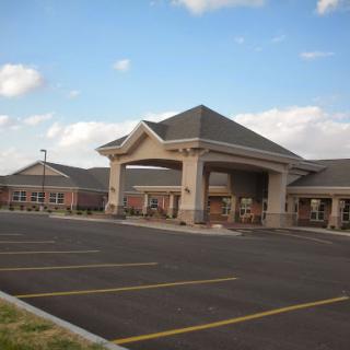 A well-structured hotel with a spacious parking lot beneath a partly cloudy sky.
