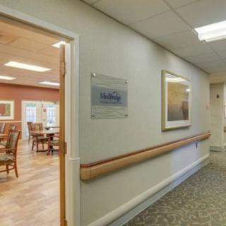A view of a hallway in a nursing home facility with an open doorway leading to a dining area.