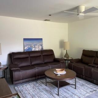 A cozy living room with leather sofas, a coffee table, and modern decor.