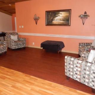 A cozy living room with patterned chairs, wall art, and wood flooring.