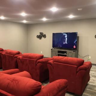 A cozy home theater setup with red chairs and a large TV.