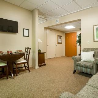 A cozy living room with a sofa, dining table, and wall-mounted television.